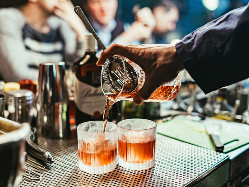 straining cocktails into glasses